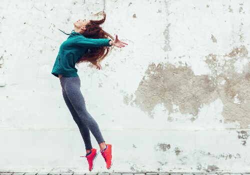 Person jumping against weathered concrete wall Person jumping against weathered concrete wall