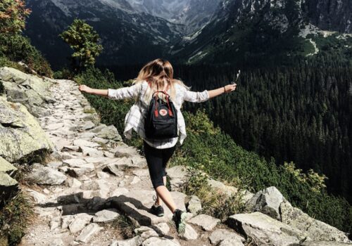 Backpack-clad woman stepping over rocks Backpack-clad woman stepping over rocks