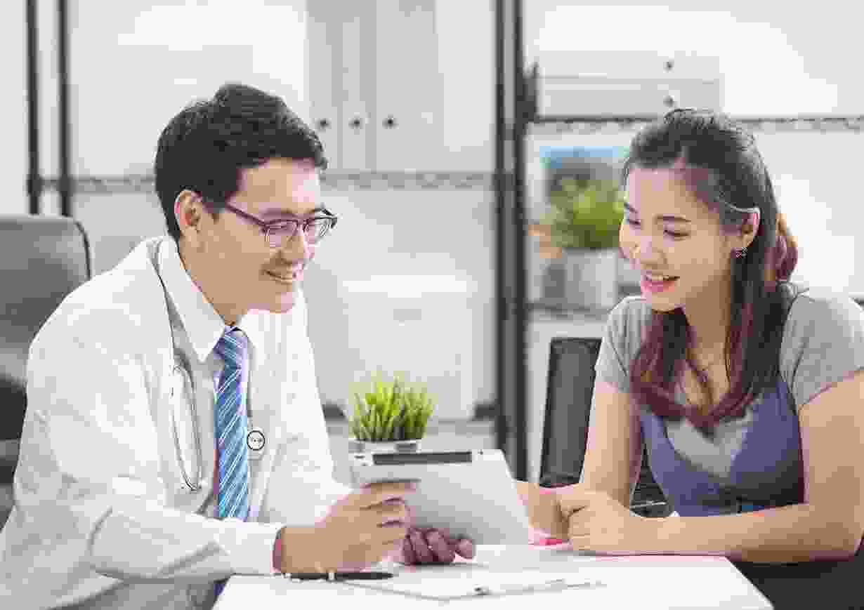 Doctor consulting smiling female patient with tablet Doctor consulting smiling female patient with tablet