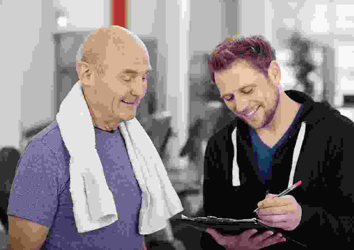 Personal trainer reviewing workout with older man Personal trainer reviewing workout with older man