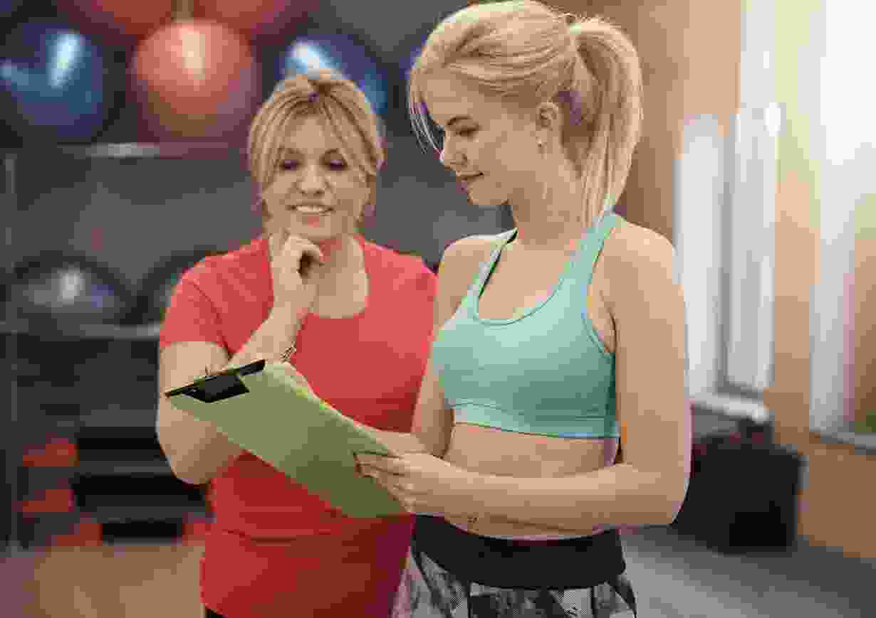 Female trainer reviewing workout plan with client Female trainer reviewing workout plan with client