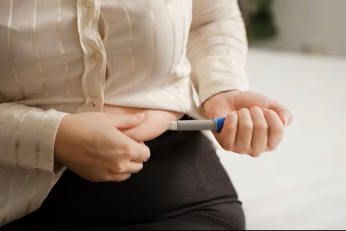 Person injecting medication into abdomen with pen